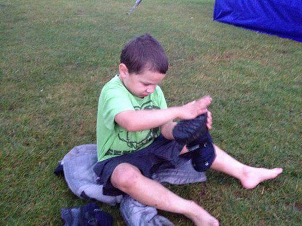 little boy puring water out of his wellington boots