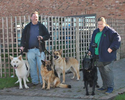 2 people holding 4 gsd's