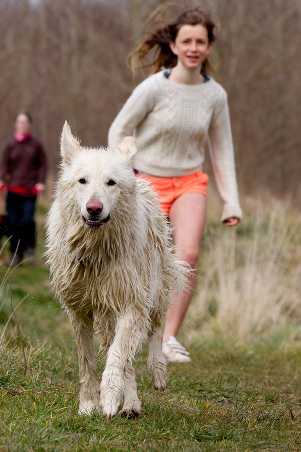 young girl enjoying running with her white german shepherd